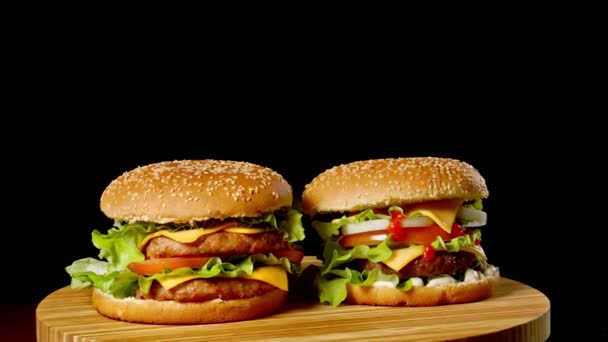 Två hantverk nötkött hamburgare på träbord isolerade på mörka gråskala bakgrund. — Stockvideo