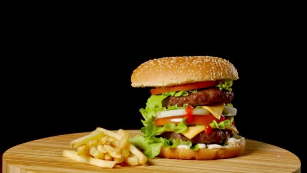 Hamburguesa artesanal de res y papas fritas, salsa aislada sobre fondo negro. comida rápida — Vídeos de Stock