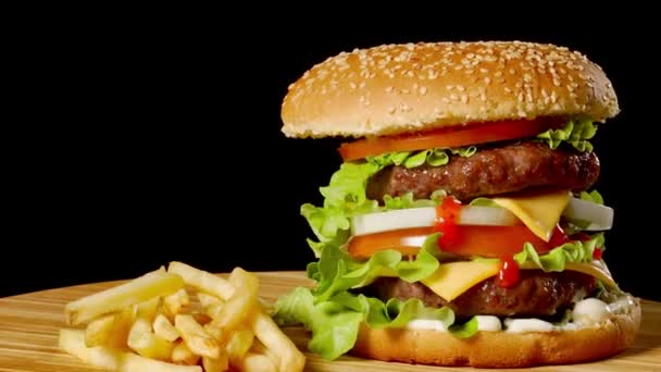 Ambachtelijke rundvlees hamburger en frietjes, saus geïsoleerd op zwarte achtergrond. fastfood — Stockvideo