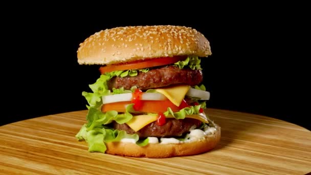 Cheeseburger mit Speck auf dunklem Hintergrund. Nahaufnahme. Makroschießen. — Stockvideo