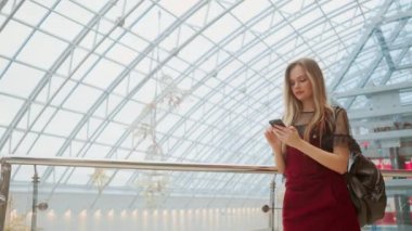 Telefon alışveriş merkezinde, bakarken gülümseyen çanta satın almalarla, holding mutlu genç kız. İyi haber, okuma mesaj, mesaj aldı. Yatay fotoğraf banner web sitesi header tasarımı için.