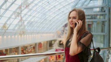 smartphone üzerinde konuşmak ve alışveriş merkezinde alışveriş torbaları ile oturan güzel kız