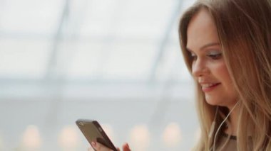 Kız yakın çekim ile cep telefonu kısa mesaj yazma. Bir akıllı telefon ekran izlemek. Havaalanında cep telefonu üzerinden video konferans