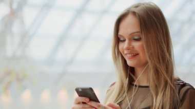 Kız yakın çekim ile cep telefonu kısa mesaj yazma. Bir akıllı telefon ekran izlemek. Havaalanında cep telefonu üzerinden video konferans