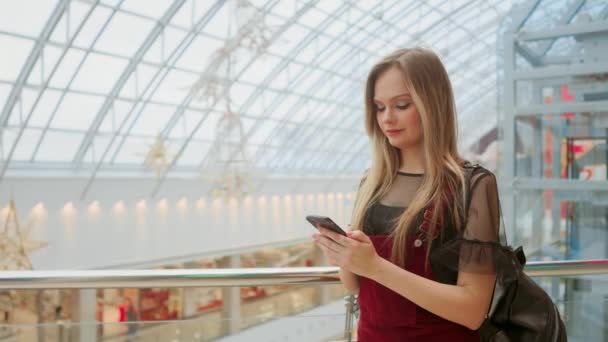 Menina usar telefone celular, imagem borrão de dentro do shopping como fundo . — Vídeo de Stock