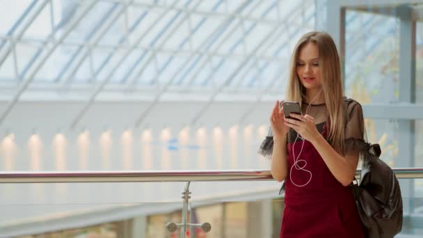 Glückliches Teenager-Mädchen, das Taschen mit Einkäufen in der Hand hält und lächelt, während es im Einkaufszentrum auf das Telefon schaut. erhielt gute Nachrichten, Nachrichten lesen, SMS schreiben. horizontales Foto-Banner für Website-Header-Design — Stockvideo