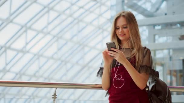 Mädchen verwenden Mobiltelefon, verschwommenes Bild im Inneren der Mall als Hintergrund. — Stockvideo