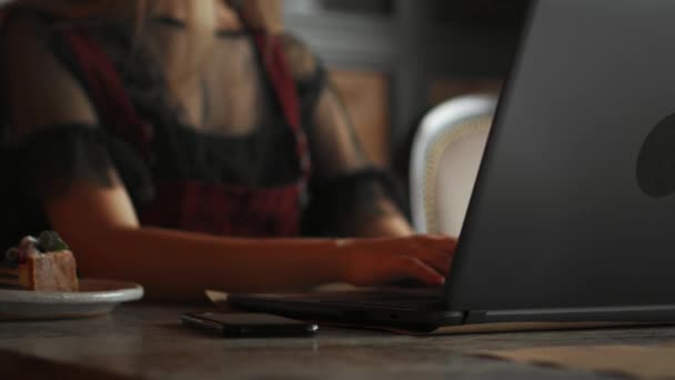 年轻女人穿着漂亮的衣服用手提电脑。在室外咖啡店的笔记本电脑上工作的女性. — 图库视频影像