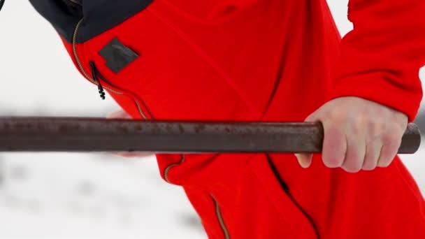 Un jeune homme beau dans une veste de sport et un pantalon noir en hiver sur une plate-forme ouverte effectue otshimaniya sur des barres parallèles. Au ralenti. Une caméra de gros plan se déplace le long du corps de l'athlète . — Video
