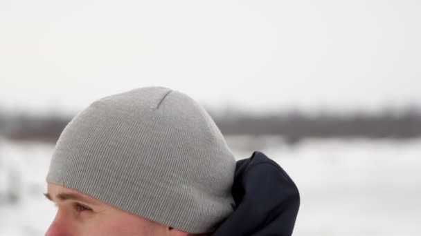 Un giovane bell'uomo in giacca sportiva e pantaloni neri in inverno su una piattaforma aperta esegue otshimaniya su sbarre parallele. Al rallentatore. Close-up camera si muove con i suoi movimenti . — Video Stock