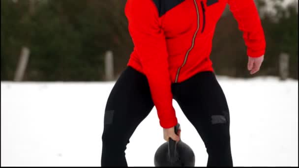 Aantrekkelijke sportman met waterkoker bell oefenen in de fitness buiten winter en sneeuw — Stockvideo