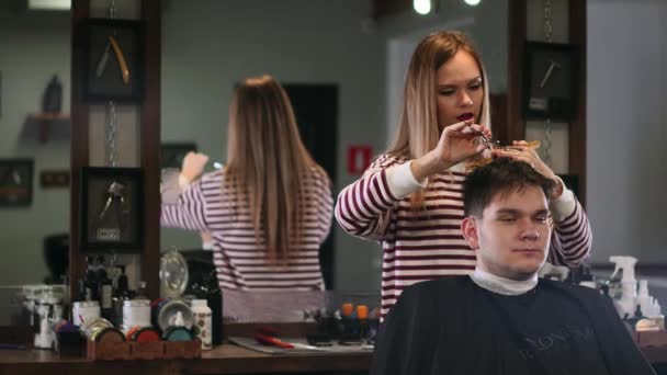 Vrouw Kapper snijdt de haren van een man zit in een lade in een mens-schoonheidssalon. — Stockvideo