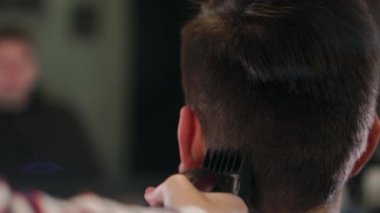 Kuaför araçları. Erkek elinde elektrikli saç kesme makineleri fırçalama kapatın. Kuaför saç makineyi sonraki istemci için hazırlamak. Adam temiz siyah tıraş makinesi