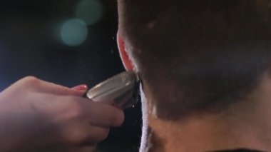 Kuaför araçları. Erkek elinde elektrikli saç kesme makineleri fırçalama kapatın. Kuaför saç makineyi sonraki istemci için hazırlamak. Adam temiz siyah tıraş makinesi