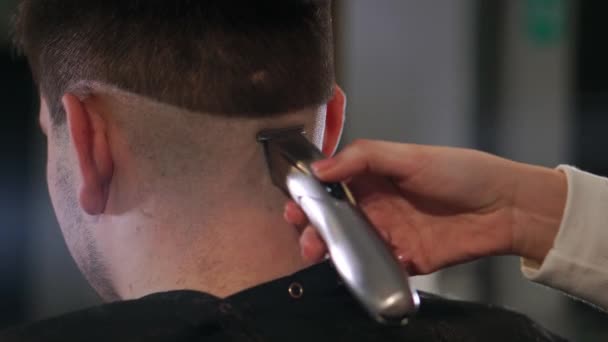 Vista da vicino sull'acconciatura maschile in un negozio di barbiere con trimmer professionale. Taglio di capelli di uomini a salone di capelli con taglierina elettrica. Curare i capelli . — Video Stock