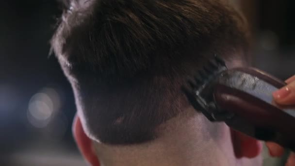 Vista close-up no penteado masculino em uma barbearia com aparador profissional. Corte de cabelo Mans no salão de cabeleireiro com cortador elétrico. Arrumar o cabelo . — Vídeo de Stock