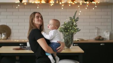 Anne ve bebek oğlu eğleniyor ve evde oynamak. Küçük çocuk 2 yaş oyun anne kollarını ile evde büyük bir pencere yakınında