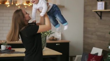 Anne ve bebek oğlu eğleniyor ve evde oynamak. Küçük çocuk 2 yaş oyun anne kollarını ile evde büyük bir pencere yakınında