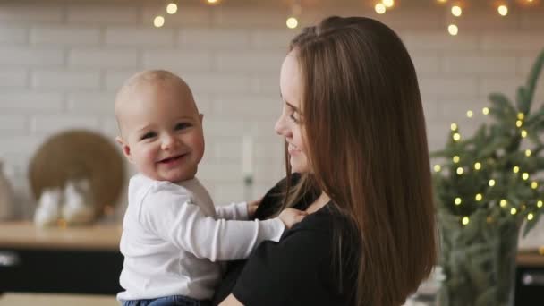 Moeder en haar zoontje met plezier en spelen thuis. Klein kind 2 jaar oud spelen met zijn moeder armen thuis in de buurt van een groot raam — Stockvideo