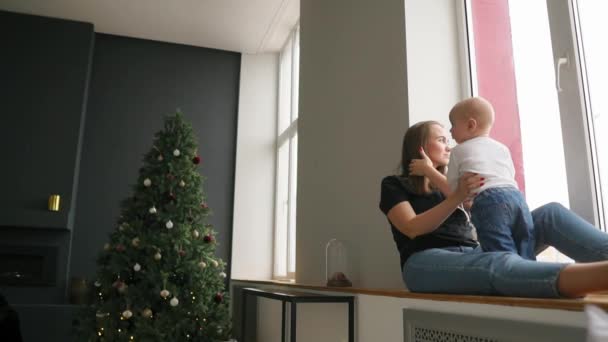 Bambino di 9 mesi che guarda la telecamera. con un tocco di sole, tenuto dalla mamma . — Video Stock