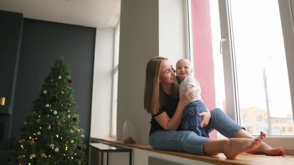 Young Mother Sitting Her Son Window Sill Decorated Christmas Wreath — Stock Video