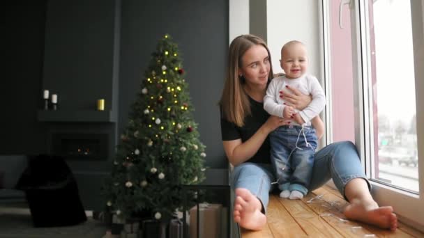 Bambino di 9 mesi che guarda la telecamera. con un tocco di sole, tenuto dalla mamma . — Video Stock