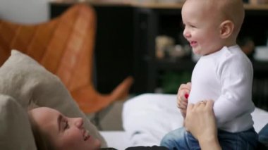 mutlu bir aile. Anne ile bebeği yatak odasında oynarken. Gülerek ve gülümseyerek.