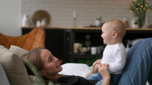 Лучшие моменты из жизни, любящая счастливая молодая мать обнимает кормящего сына, на белоснежном одеяле, на белом фоне. Концепция любви, семьи и счастья Концепция: дети, дети, ребенок, младенцы — стоковое видео