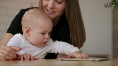 Genç beyaz anne bebek oğlu ile Tablet kullanarak. Ağır çekim 120 fps. Onun çocuk dijital Tablet gösterilen anne. Çocuk ve teknoloji kavramı. Yürümeye başlayan çocuk. Sinematik aile