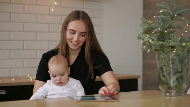 Moeder en baby zijn op zoek om te spelen en te lezen tablet computer op de bank thuis — Stockvideo