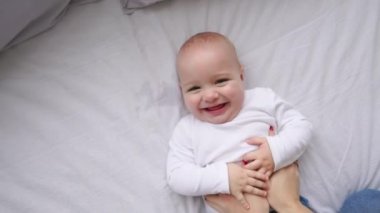 Yeni doğmuş bir bebek yatakta yatarken kameraya bakıyor ve çevresinde beyaz bir çarşaf üzerinde yukarıdan görüntüleyin. Bebek bilir dünya, üstten görünüm