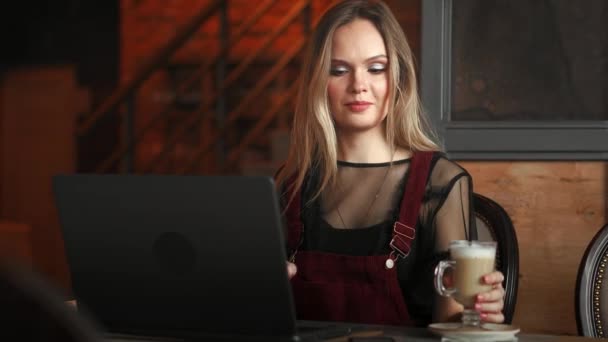Focused attentive woman in headphones sits at desk with laptop, looks at screen, makes notes, learns foreign language in internet, online study course, self-education on web, consults client by video — Stock Video
