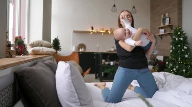 Neşeli genç gülümseyen anne ile sarılma mutlu gülen bebek portresi. Saf sevgi ve mutluluk sahnesi. Aile, annelik ve yaşam tarzı kavramı.