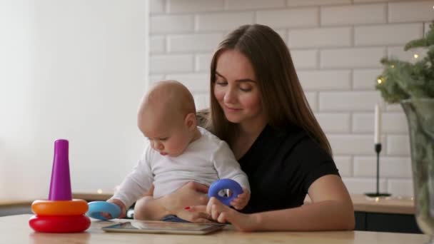 Μητέρα και το μωρό ψάχνετε για να παίξει τον υπολογιστή tablet στον καναπέ στο σπίτι — Αρχείο Βίντεο