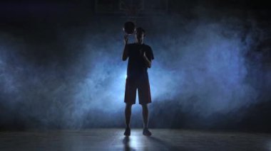 Basketbol oyuncu dönen topu onun parmağına, ışıldak Karanlık sisli oda görüntüleri kapat