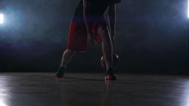 一个年轻的成年男子, 篮球运动员运球, 黑暗的室内篮球场冒烟。慢动作 — 图库视频影像