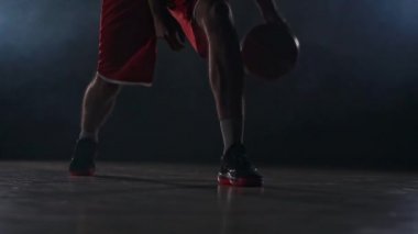 Spor giyim ve spor ayakkabı prokipyvaet basketbol topu duman yavaş çekimde basketbol sahasında bacaklarının arasına Erkek atlet
