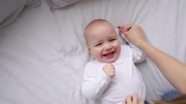 Bebek beyaz bir yatakta yatarken ve kamera yukarıdan yavaş hareket seyir gülüyor beyaz t-shirt
