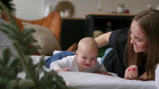 Ibu muda memeluk anaknya yang baru lahir. Ibu menyusui bayi. Wanita dan anak baru lahir santai di kamar tidur putih. Keluarga di rumah. Cinta, kepercayaan dan konsep kelembutan. Tidur dan tekstil untuk pembibitan . — Stok Video