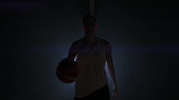 Jogador de basquete masculino se movendo na fumaça na câmera batendo a bola sobre o chão parquet em câmera lenta Steadicam tiro — Vídeo de Stock