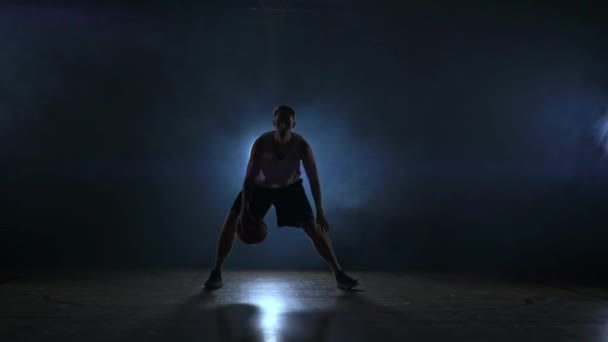 Un jugador de baloncesto en solitario hace algunos movimientos de driblado delante de la cámara — Vídeos de Stock