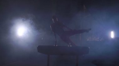Erkek jimnastikçi kulplu beygir spin performans üzerinde Olimpiyat programdan egzersizleri yapar ve ağır çekimde rulo