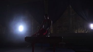Karanlık bir odada duman yavaş çekimde kulplu beygir egzersiz erkek jimnastikçi gerçekleştirir. Spor Sağlık ve başarı için
