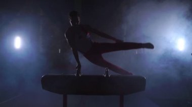 erkek jimnastikçi atlet amut ve rotasyon kulplu beygir koyu arka planı ve duman yavaş hareket üzerinde gerçekleştirir