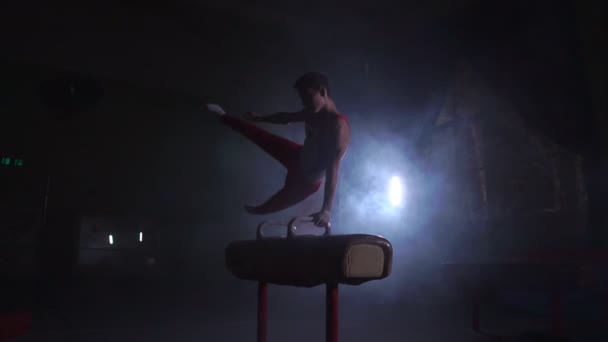 Mannelijke Turner atleet voert handstand en spin op voltige op een donkere achtergrond en rook in slow motion. Olympisch programma — Stockvideo