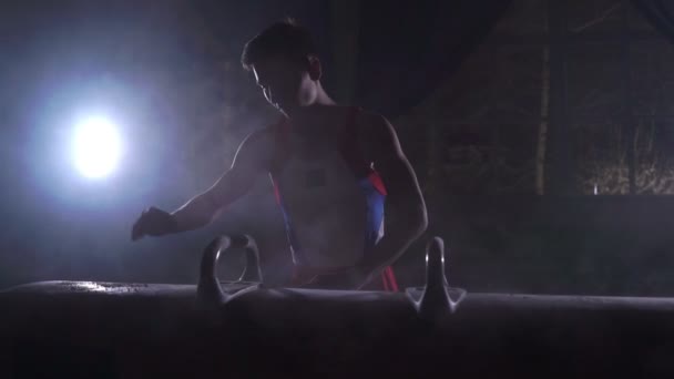 Atleta gimnasta masculino realiza handstand y girar en caballo Pommel sobre un fondo oscuro y el humo en cámara lenta. Programa Olímpico. Preparación para el ejercicio — Vídeo de stock