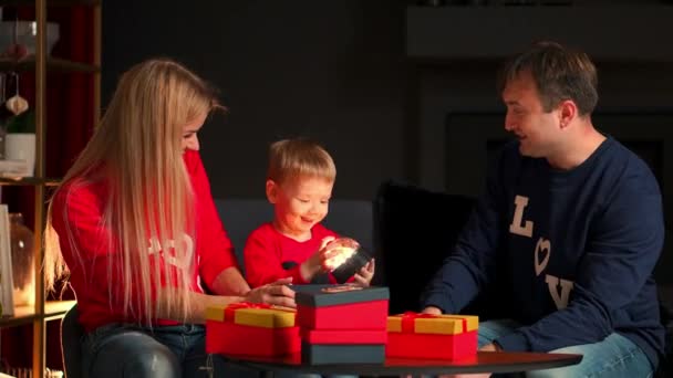 Famiglia mamma papà e figlio a Natale regali aperti a casa seduti sul divano all'interno di Natale. Atmosfera calda e accogliente — Video Stock