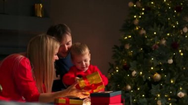 Anne baba ve oğul evde açık hediyeler Noel, Noel iç kanepede oturuyor. Sıcak ve rahat ev atmosfer