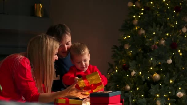 Mama tata i syn na Boże Narodzenie prezenty w domu siedzi na kanapie w Boże Narodzenie wnętrza. Ciepła i przytulna atmosfera domu — Wideo stockowe