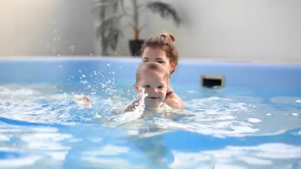 Милый мальчик наслаждается с матерью в бассейне . — стоковое видео